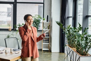Afro-amerikan beslenme uzmanları ofisteki ek maddeleri tutarken akıllı telefondan danışmanlık yapıyorlar.