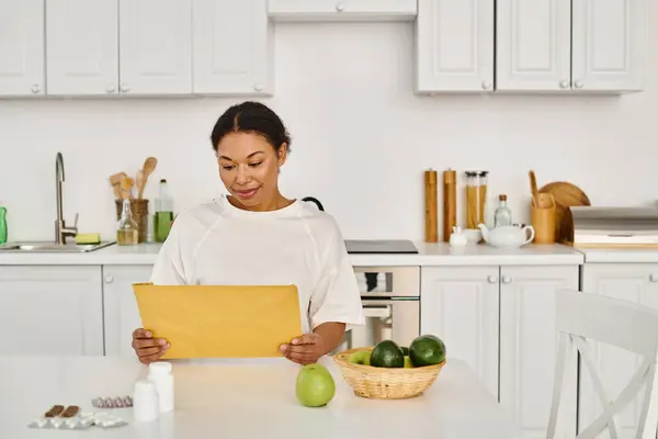 ブルネット アフリカ系アメリカ人女性は サプリメントや果物の近くの食事計画で封筒を見ています — ストック写真