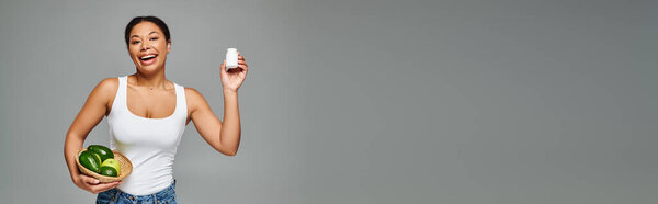 счастливый африканский диетолог с зелеными фруктами и добавками на сером, горизонтальном баннере