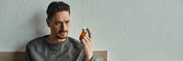 Hombre Pensativo Mirando Botella Con Medicamentos Mientras Está Sentado Dormitorio — Foto de Stock