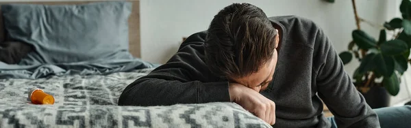 Stock image bearded man suffering from pain and leaning on grey blanket on bed in modern bedroom, ache banner