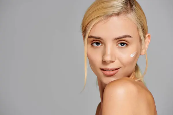 stock image portrait woman face with radiant skin and lotion on her cheek looking playful in grey background