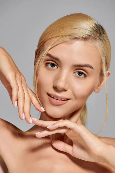 stock image beautiful young woman with gray eyes and perfect skin posing with hands near face on gray background