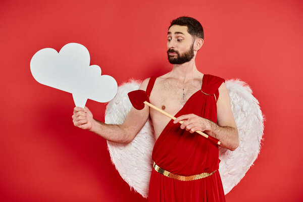 задумчивый амур со стрелой в форме сердца, смотрящий на белый пустой мыльный пузырь на красном фоне