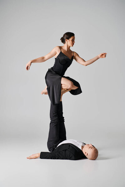 Dynamic duo, couple of acrobats performing balance act in a studio setting with grey backdrop