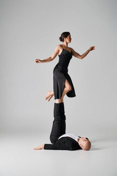 athletic duo, couple of acrobats performing balance act in a studio setting with grey backdrop