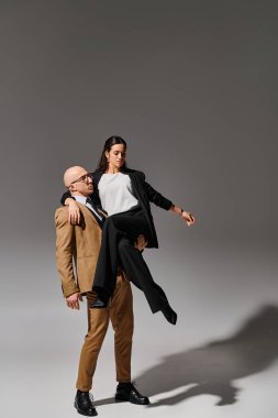 Resmi kıyafetli bir adam esmer ve zarif dansçı performans sırasında dengede duruyor.