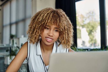 Ofisteki bilgisayardaki video görüşmesi sırasında gülümseyen Afro-Amerikan iş kadını.