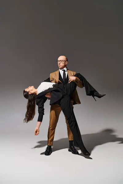 グレーの背景にスタジオで劇的なダンスパフォーマンスでエレガントなビジネスカップル — ストック写真
