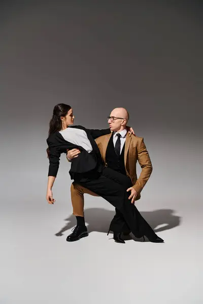 Mężczyzna Garniturze Okulary Wspieranie Brunetka Podczas Tańca Studio Szary — Zdjęcie stockowe