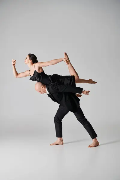 男性とのダンスパフォーマンス中に優雅にバランスをとる黒いドレスの裸足の若い女性 — ストック写真