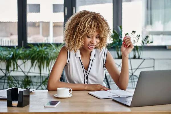 在现代办公室里 快乐的非洲裔美国女商人 带着牙套 在笔记本电脑旁边看笔记 — 图库照片