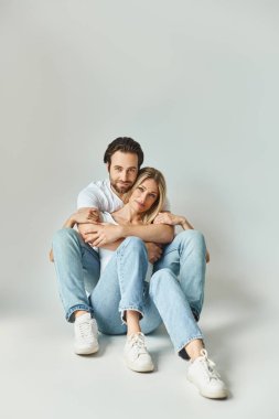 Bir erkek ve bir kadın birbirlerine kenetlenmiş oturuyorlar, fiziksel yakınlıkları aracılığıyla sevgi ve sevgiyi ifade ediyorlar..