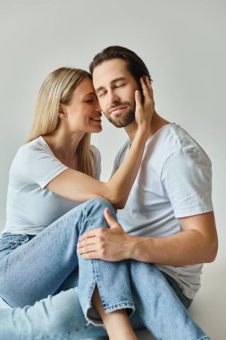Romantik bir havayı somutlaştıran bir erkek ve kadın, erkeğinin yanağına dokunan bir kadın, yakın otururlar.