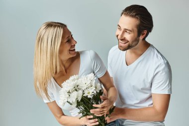 Bir erkeğin mutlu bir kadının yanında bir buket çiçeği tutarken yakaladığı romantik bir an..