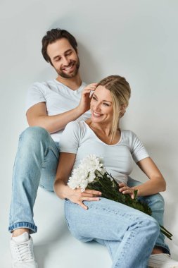 Romantik bir adam, elinde güzel bir buket çiçek tutan bir kadının yanında oturur, sevgi ve şefkat dolu bir aura yayar..