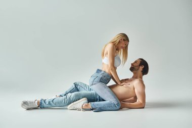 Bir erkek ve bir kadın, şehvetli bir aura yayarak, huzurlu bir anda yerde yan yana otururlar..