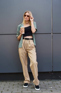 Duvara yaslanmış bir kadın, huzurlu bir anda bir fincan kahvenin tadını çıkarıyor..