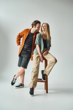Romantik bir çift, erkek ve kadın, bir taburede birbirlerine yakın oturmuşlar, yakınlık ve bağ havası yayıyorlar..