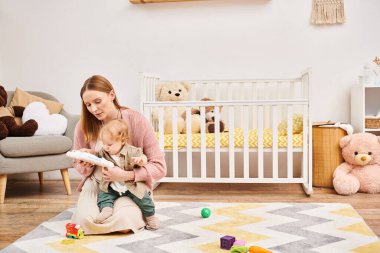 Genç anne, bebek beşiğinin yanında sevimli çocukla oynuyor. Bebek odasında, bebek odasında, mutlu annelik.