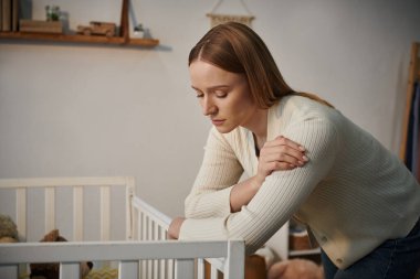 depressed woman standing near crib with soft toys in bleak nursery room at home, frustration clipart