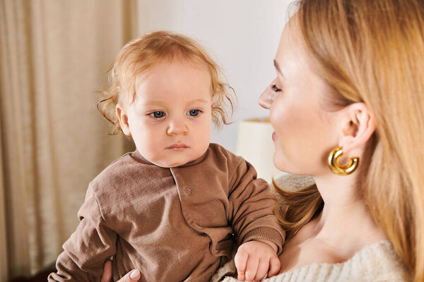 молодая привлекательная женщина, держащая в руках милого маленького сына в детской комнате дома, счастливое материнство