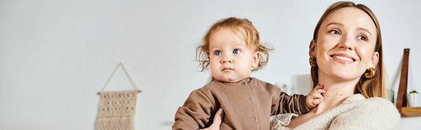 счастливая молодая мать держит и обнимает маленького сына в уютной детской комнате, горизонтальный баннер