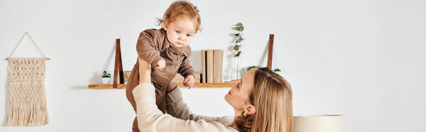 молодая радостная мать играет и веселится с малышом сыном в детской комнате, горизонтальное знамя