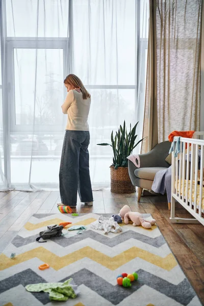 stock image depressed woman grieving in nursery room near soft toys and baby crib at home, frustration