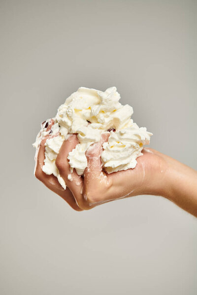object photo of sweet gourmet whipped cream in hand of unknown female model on gray backdrop