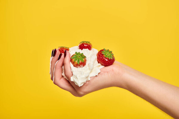 object photo of delicious sweet red strawberries in whipped cream in hands of unknown woman