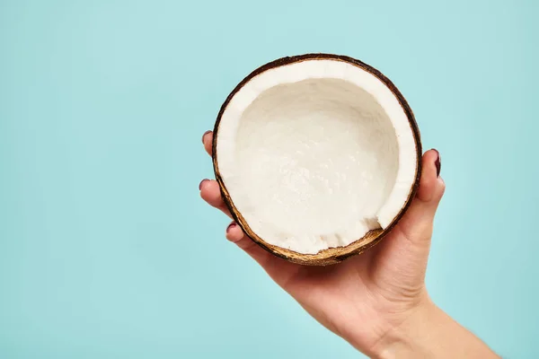 stock image object photo of delicious piece of coconut in hand of young unknown woman on vibrant blue backdrop