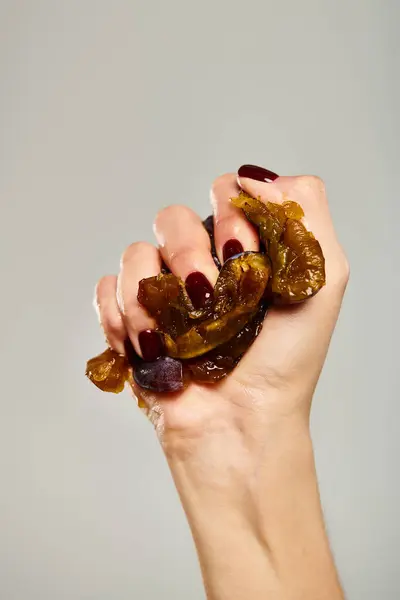 stock image young unknown woman with nail polish squeezing fresh juicy plum in her hand on gray background