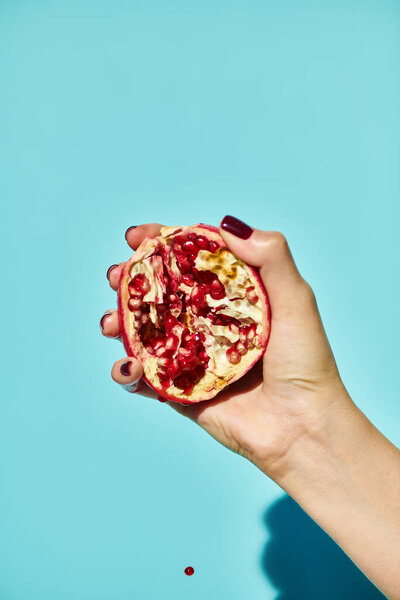object photo of red delicious fresh pomegranate in hand of unknown female model with nail polish