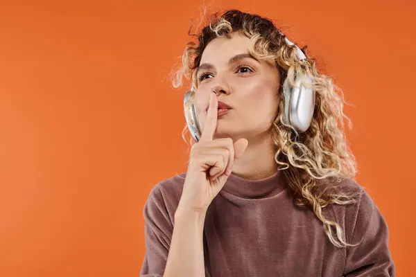 オレンジ色のハッシュサインを示すワイヤレスヘッドフォンでヘアリスニングミュージックを持つ魅力的な女性 — ストック写真