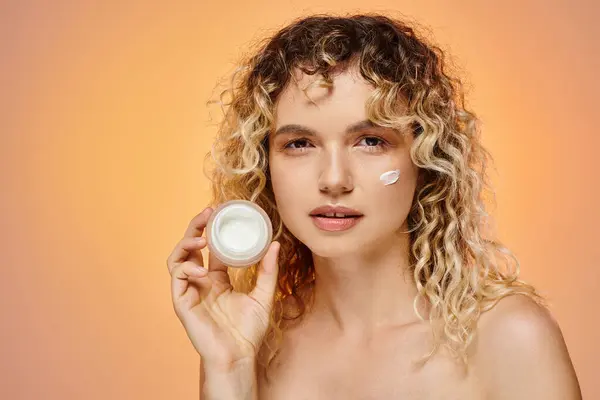 stock image sensual woman with curly hair and perfect skin showing jar of face cream on yellow and pink