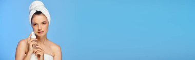 Kafasında havlu olan çekici bir kadın ve yüzünde mavi köpük olan temiz bir cilt taşıyıcısı.