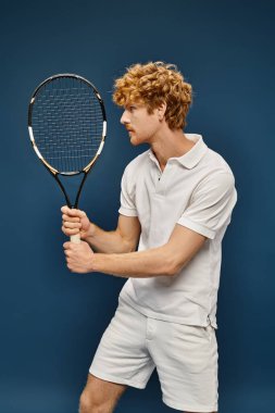 Aktif aristokrat kızıl saçlı beyaz giysili adam mavi, klasik moda ile tenis oynuyor.