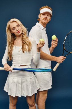 Beyaz elbiseli aristokrat genç çift tenis raketleri ve topları mavi, eski para modasında
