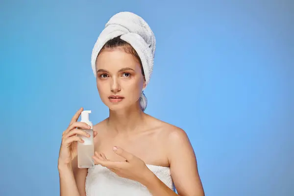 stock image attractive woman with towel on head and perfect face holding dispenser with cosmetic foam on blue