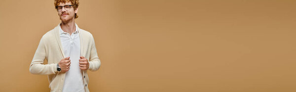 довольный рыжий мужчина в очках и старом костюме в стиле денег, смотрящий в камеру на бежевом, баннере