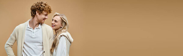 счастливая блондинка и рыжий мужчина в старой одежде деньги стиль улыбаясь друг другу на бежевый, баннер