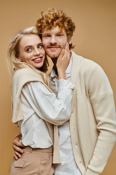 stock image fashionable couple in trendy old money style attire smiling and embracing on grey backdrop