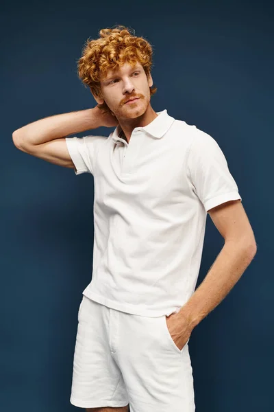 stock image wealthy redhead man in white attire with hand in pocket looking away on blue, timeless fashion