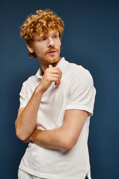 вдумчивый рыжий мужчина в белой стильной одежде смотрит вдаль на голубую старую моду в стиле денег