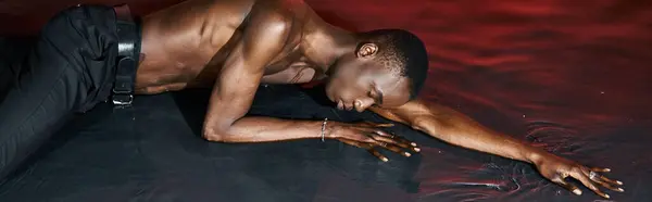 stock image alluring african american man in wet pants lying on water surface with closed eyes, lights, banner