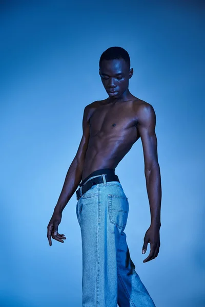 Ung Afrikansk Amerikansk Man Trendiga Jeans Poserar Blå Vattnig Bakgrund — Stockfoto