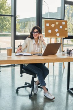 A businesswoman in a modern office focuses intently on her laptop, embodying the franchise concept. clipart