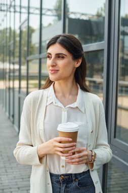 A businesswoman relishes a cup of coffee in a modern outdoor office setting, embodying the franchise concept. clipart