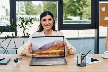 Masada oturan bir iş kadını, dizüstü bilgisayarla meşgul, modern ofis ve bayilik kavramını somutlaştırıyor..